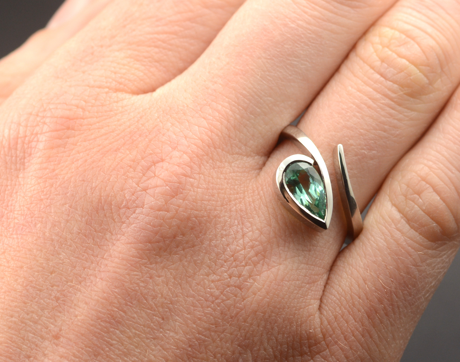 Contemporary engagement ring with pear shaped green tourmaline on hand