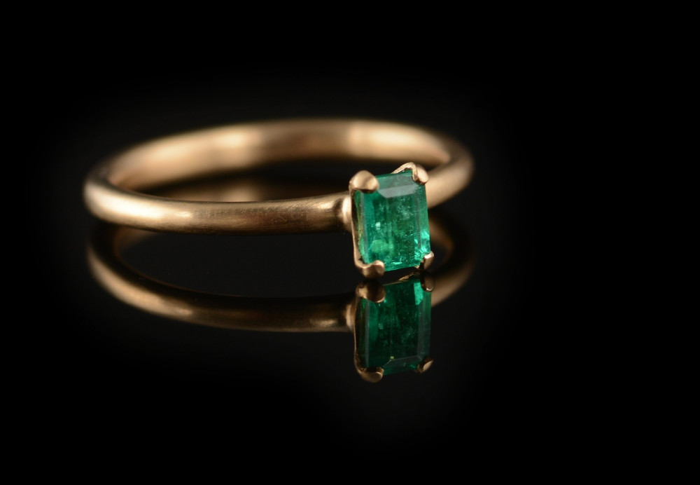 Emerald and rose gold claw engagement ring