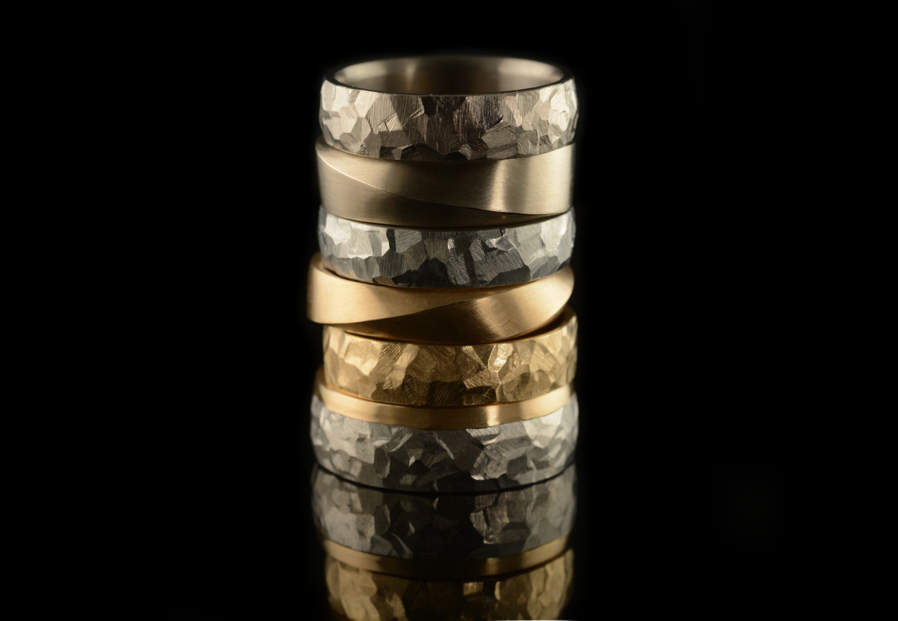 Stack of mens mobius and hammered wedding rings in gold and platinum