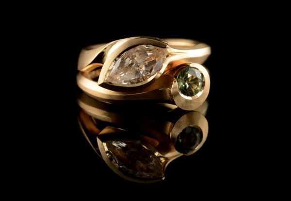 Unusual hand carved gold engagement ring with marquise diamond and fitted carved wedding ring with round green sapphire